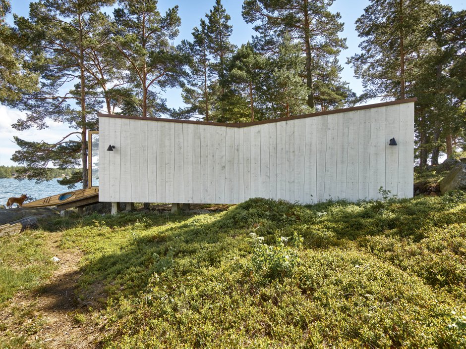 A kayak house with a wooden facade of conical grey planks close to the water in the stockholm archipelago